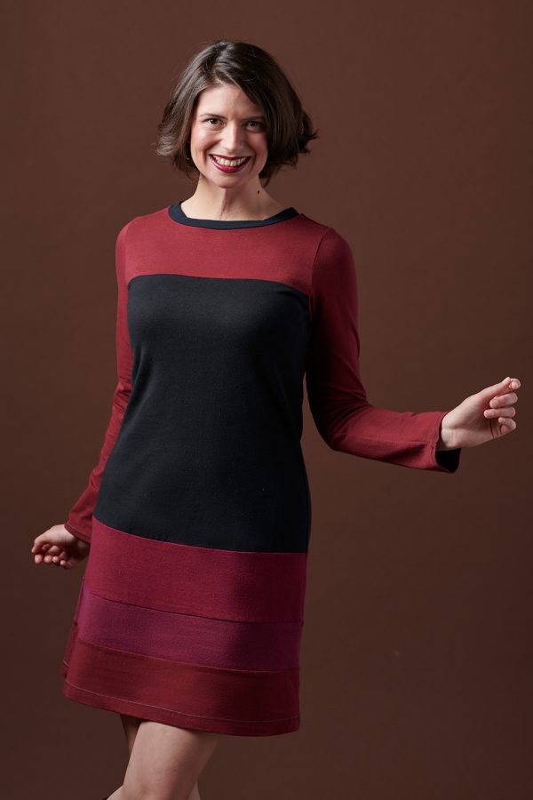 long sleeve hemp dress in reds and black on smiling lady with brown background