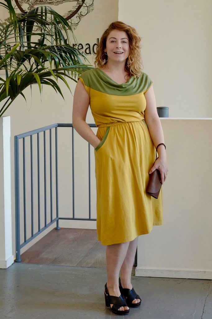 pretty lady in yellow and green wildflower dress with cowl neck, pockets, and colorblocking of organic fabrics
