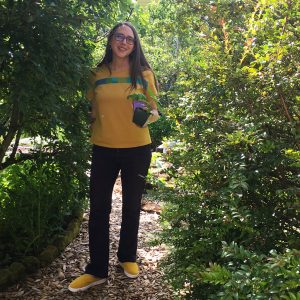 Amy with yellow Mineral Top and yellow Bendy shoes, holding plants in her garden